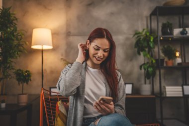 Evde genç bir kadın cep telefonu mesajlaşması kullanıyor ya da internette geziniyor