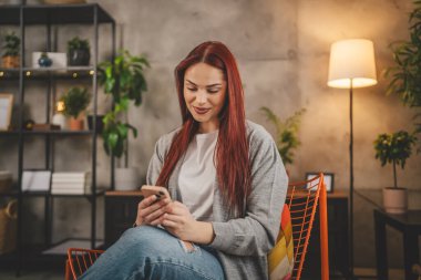 Evde genç bir kadın cep telefonu mesajlaşması kullanıyor ya da internette geziniyor