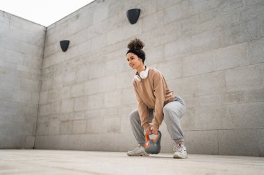 Kafkasyalı genç bir bayan sporcu gün içinde dışarıda Rus çanı Girya Kettlebell ağırlık egzersizi ile antrenman yapıyor.