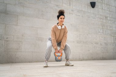 Kafkasyalı genç bir bayan sporcu gün içinde dışarıda Rus çanı Girya Kettlebell ağırlık egzersizi ile antrenman yapıyor.