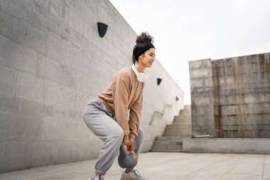 Kafkasyalı genç bir bayan sporcu gün içinde dışarıda Rus çanı Girya Kettlebell ağırlık egzersizi ile antrenman yapıyor.