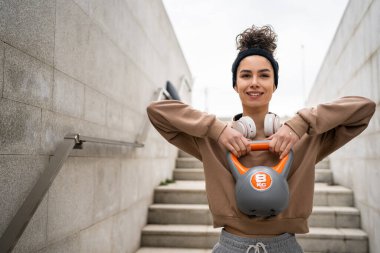 Kafkasyalı genç bir bayan sporcu gün içinde dışarıda Rus çanı Girya Kettlebell ağırlık egzersizi ile antrenman yapıyor.