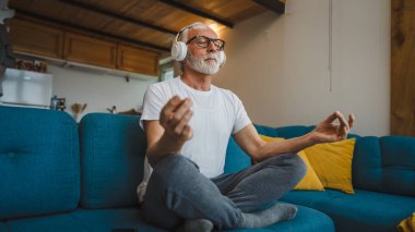 Üst düzey Kafkas erkek gözleri, kulaklıklarla evde otururken yoga ya da meditasyon için kapalı. Gerçek insanların iç huzuru ve denge konsepti.