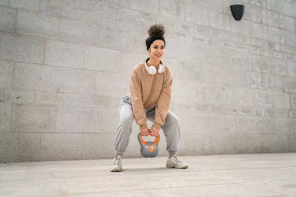 Kafkasyalı genç bir bayan sporcu gün içinde dışarıda Rus çanı Girya Kettlebell ağırlık egzersizi ile antrenman yapıyor.