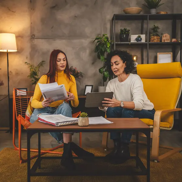 İki genç beyaz kadın öğrenci akıl hocasıyla birlikte evde oturup ders kitaplarına bakıyorlar. Sınav öğrenme eğitimine hazırlanıyorlar. Gerçek insanlar yer kopyalıyor.