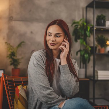 Evdeki bir genç kadın cep telefonu kullanıyor. Akıllı telefon konuşuyor.