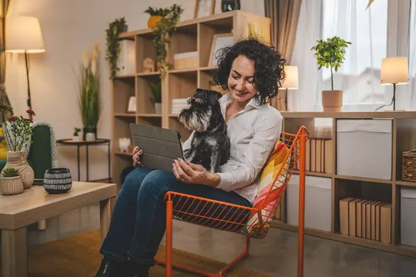 portrait adult caucasian woman use digital tablet with pet dog at home