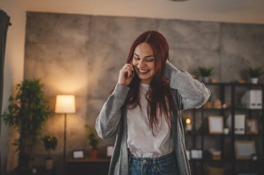Evdeki bir genç kadın cep telefonu kullanıyor. Akıllı telefon konuşuyor.
