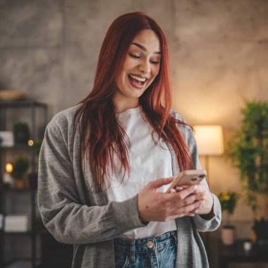 Evde genç bir kadın cep telefonu mesajlaşması kullanıyor ya da internette geziniyor