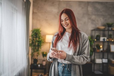 Evde genç bir kadın cep telefonu mesajlaşması kullanıyor ya da internette geziniyor