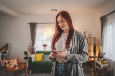 Evde genç bir kadın cep telefonu mesajlaşması kullanıyor ya da internette geziniyor