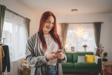 Evde genç bir kadın cep telefonu mesajlaşması kullanıyor ya da internette geziniyor