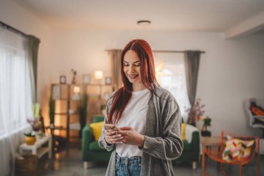 Evde genç bir kadın cep telefonu mesajlaşması kullanıyor ya da internette geziniyor