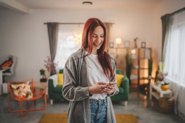Evde genç bir kadın cep telefonu mesajlaşması kullanıyor ya da internette geziniyor