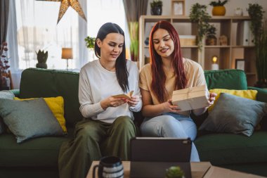 İki genç kadın arkadaş ya da kız kardeş, açık bir kutuda hediye alırlar. Açık kart okuyarak mutlu bir gülümseme, dijital tabletin önünde çevrimiçi video araması yaparlar.