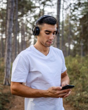 Sabah koşarken cep telefonu kullanan bir sporcunun portresi kulaklıkla müzik dinleyen atletik bir adam cep telefonu uygulaması kullanıyor