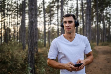 Sabah koşarken cep telefonu kullanan bir sporcunun portresi kulaklıkla müzik dinleyen atletik bir adam cep telefonu uygulaması kullanıyor