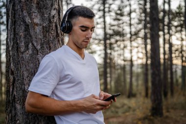 Sabah koşarken cep telefonu kullanan bir sporcunun portresi kulaklıkla müzik dinleyen atletik bir adam cep telefonu uygulaması kullanıyor