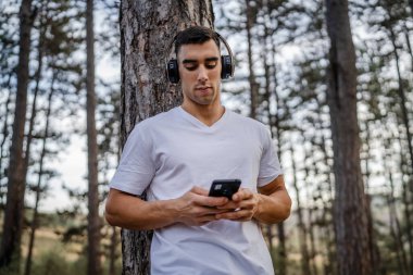 Sabah koşarken cep telefonu kullanan bir sporcunun portresi kulaklıkla müzik dinleyen atletik bir adam cep telefonu uygulaması kullanıyor