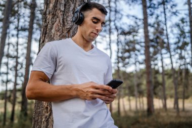 Sabah koşarken cep telefonu kullanan bir sporcunun portresi kulaklıkla müzik dinleyen atletik bir adam cep telefonu uygulaması kullanıyor