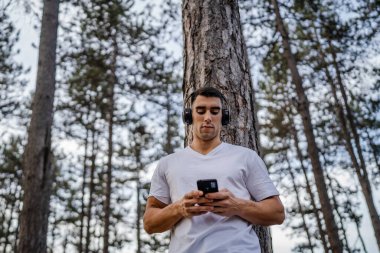 Sabah koşarken cep telefonu kullanan bir sporcunun portresi kulaklıkla müzik dinleyen atletik bir adam cep telefonu uygulaması kullanıyor