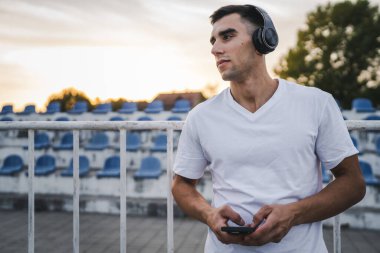 Sabah koşarken cep telefonu kullanan bir sporcunun portresi kulaklıkla müzik dinleyen atletik bir adam cep telefonu uygulaması kullanıyor