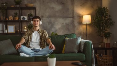 Rehberli meditasyon yapan genç bir adam evde yoga yapıyor.