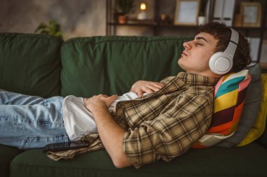 Rehberli meditasyon yapan genç bir adam evde yoga yapıyor.