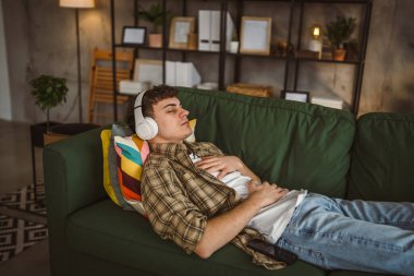 Rehberli meditasyon yapan genç bir adam evde yoga yapıyor.