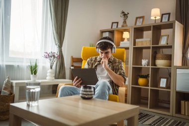 Kafkasyalı bir erkek, internet üzerinden video izleyip dijital tablet kullanıyor.