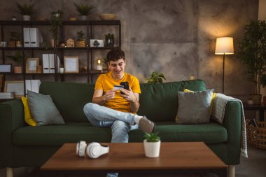 Evdeki genç adam internette kredi kartı alışverişi yapıyor.