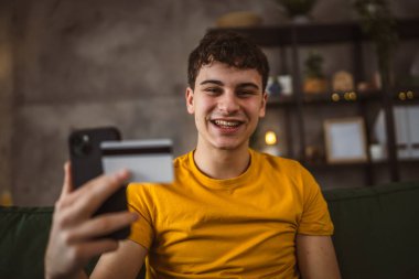 Evdeki genç adam internette kredi kartı alışverişi yapıyor.