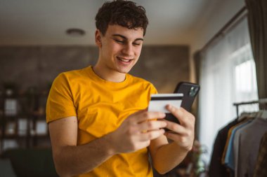 Evdeki genç adam internette kredi kartı alışverişi yapıyor.