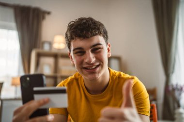 Evdeki genç adam internette kredi kartı alışverişi yapıyor.