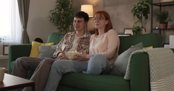 カップル慎重な男と女性はソファーベッドで自宅に座ってテレビ映画を見る — ストック動画