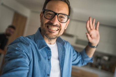 Bir yetişkin portresi, sakallı ve gözlüklü beyaz bir erkeğin mutlu bir gülümseme ile kendi portresinin fotokopisini çeker.