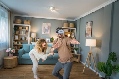 Yetişkin, beyaz, erkek, karısı ya da sevgilisiyle birlikte evde sanal gerçekliğin tadını çıkartıyor. Kafasında google 'lar olan sanal gerçekliğin tadını çıkarıyor. Modern teknoloji eğlence konsepti fotokopi alanı.