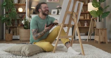 Sakallı ve bıyıklı modern bir adam boyayı evde tutuyor.
