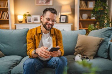 Evde kulaklıklı bir adam çevrimiçi mutlu bir gülümseme müziği dinliyor.