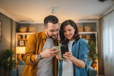 Yetişkin çift koca ve karı koca bir fincan kahve içerler cep telefonlarını interneti ararlar sosyal ağ mutlu bir gülümseme