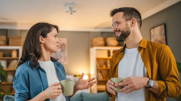 Couple man and woman husband and wife stand at home with cup of coffee talk happy smile
