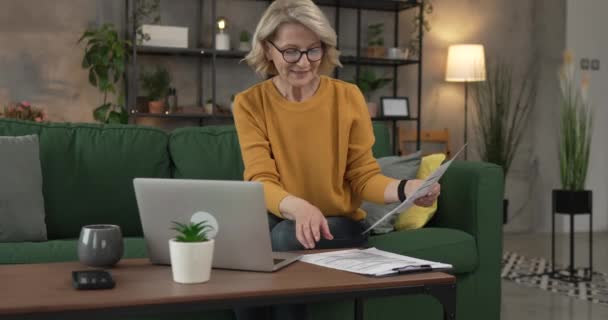 成熟した白人女性はプロジェクトの仕事のために自宅でラップトップコンピュータを使用します — ストック動画