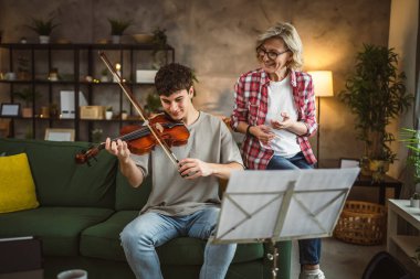Genç adam, yetişkin kadın profesörün özel dersi altında keman çalmayı öğreniyor.