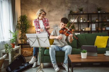 Genç adam, yetişkin kadın profesörün özel dersi altında keman çalmayı öğreniyor.