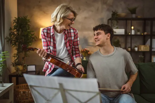 年轻男性在家中学习如何在成熟女性教授的指导下演奏小提琴 — 图库照片