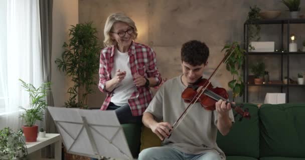 若い男は自宅で成熟した女性教授教授の指導の下でバイオリンを再生する方法を学ぶ プライベートクラスを受講 — ストック動画