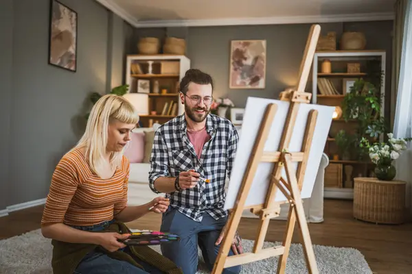 自宅でキャンバスイーゼルにカップルペイントブラシは 絵を描く方法を学ぶのに役立ちます ブラシ 幸せな男と恋に女性 彼氏やガールフレンドや夫や妻 — ストック写真