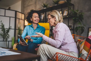 İki yetişkin kadın evlerinde oturup dijital tablet tutuyorlar. Danışman iş kadını gerçek iş ve sorunlar hakkında konuşuyor.