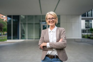 Beyaz tenli, olgun bir iş kadınının portresi dışarıda duruyor.