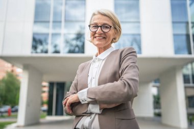 Beyaz tenli, olgun bir iş kadınının portresi dışarıda duruyor.